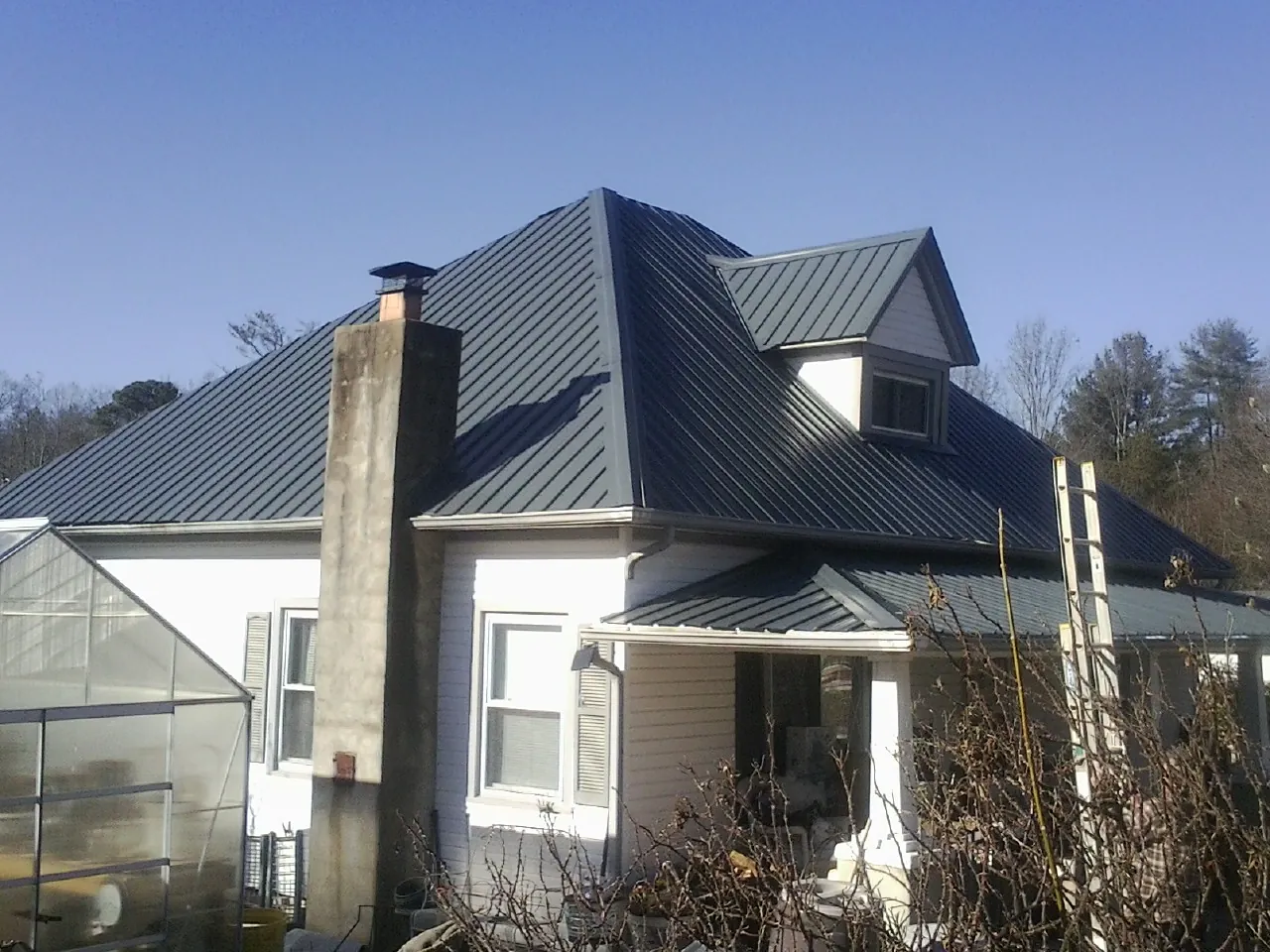Dark blue standing seam metal roof on a white farmhouse with dormer — Slate & Tile Roof Repair by Roofing Brothers in Grafton