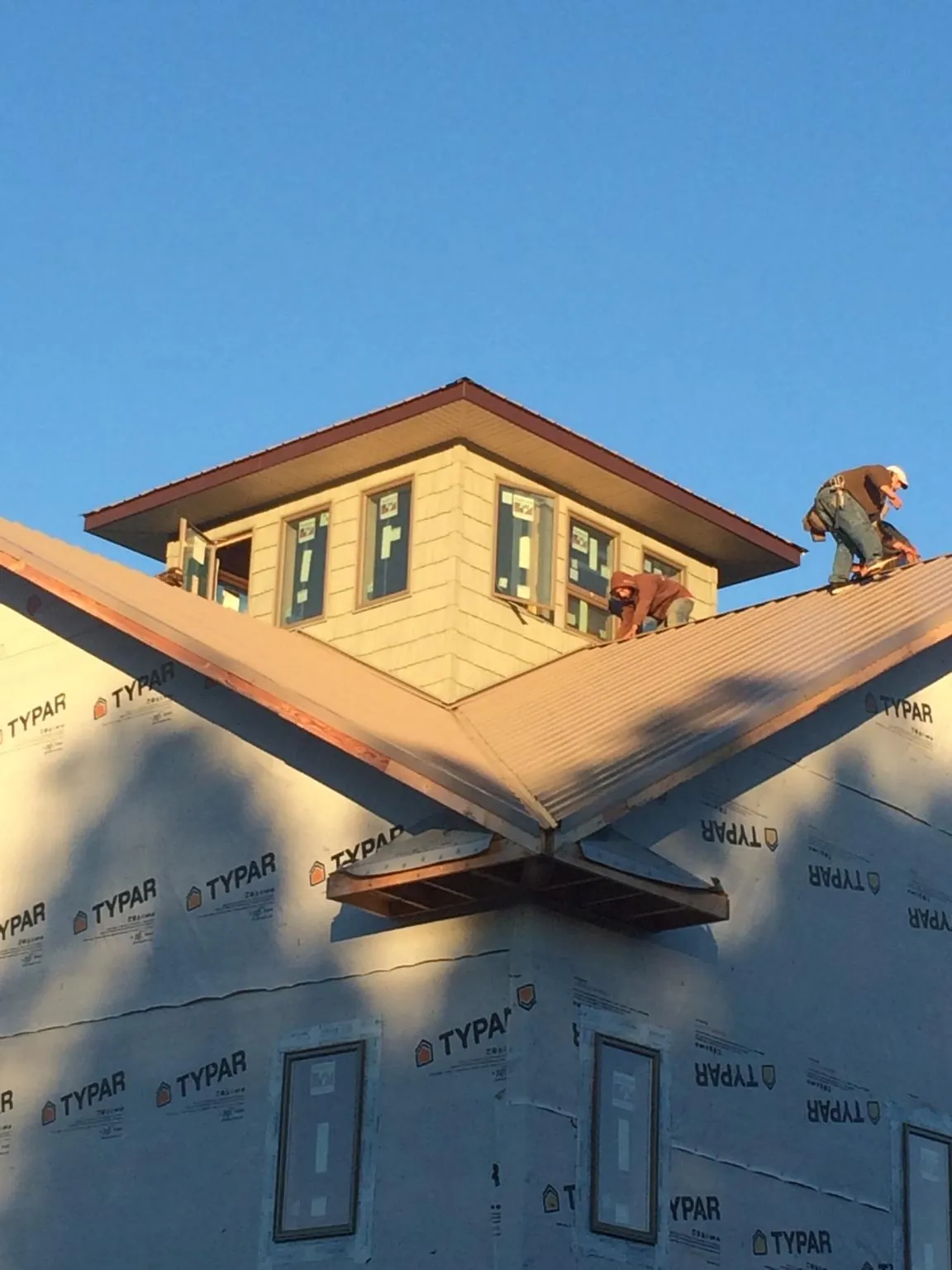Roofers working around a rooftop cupola on a new metal roof at sunset — Roof Waterproofing in Grafton by Roofing Brothers